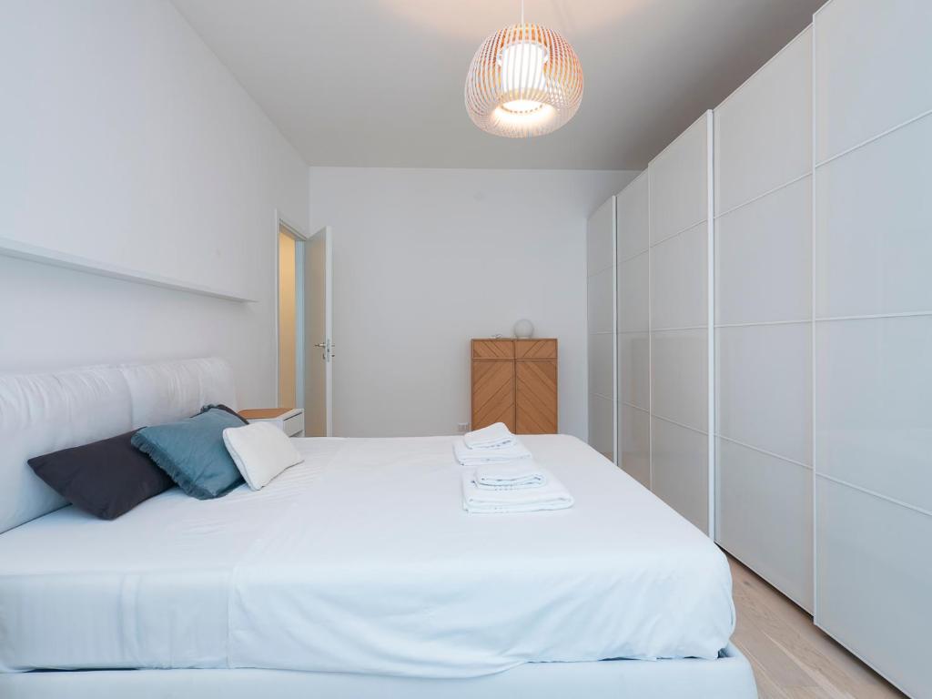 una camera da letto con un letto bianco e un lampadario di Youhosty - Grazioli 4 a Milano