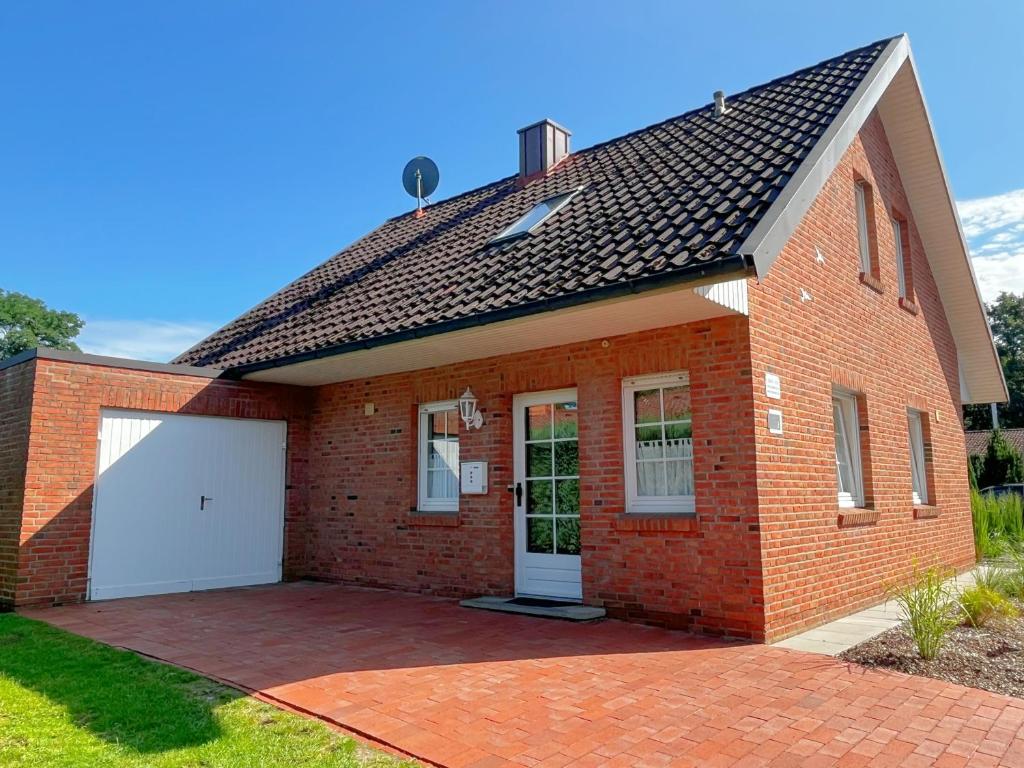 uma casa de tijolos vermelhos com uma garagem branca em Ferienhaus am See em Haselünne