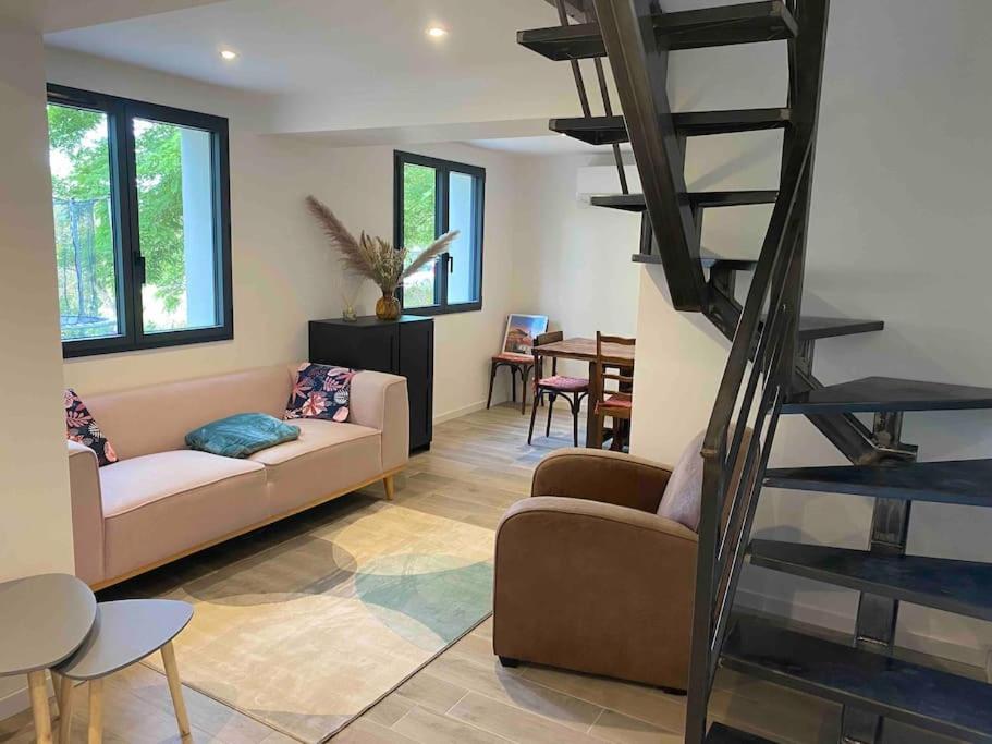 sala de estar con sofá y escalera de caracol en Maison les Acacias, en Millau