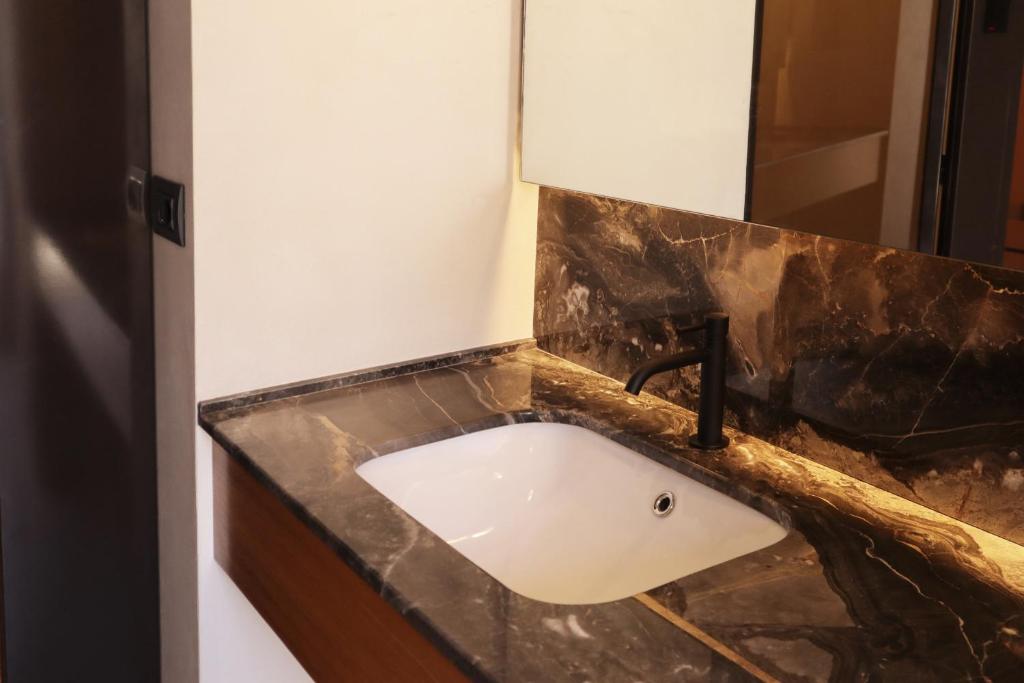 a bathroom sink with a black marble counter top at Roiss Haus Suites in Lecce