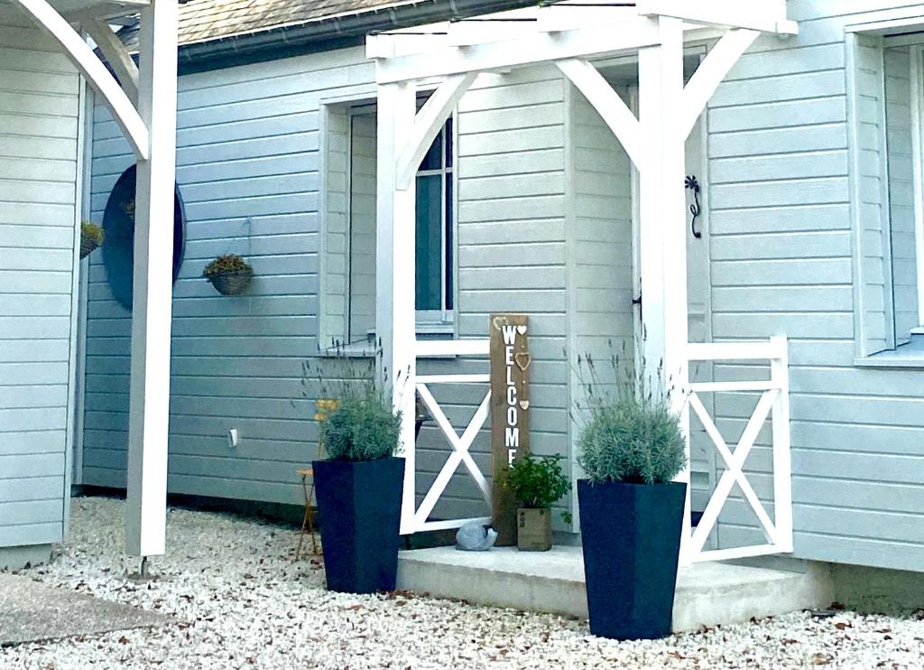 une maison bleue avec deux plantes en pot sur la terrasse couverte dans l&#39;établissement Douce Halte, à Sautron