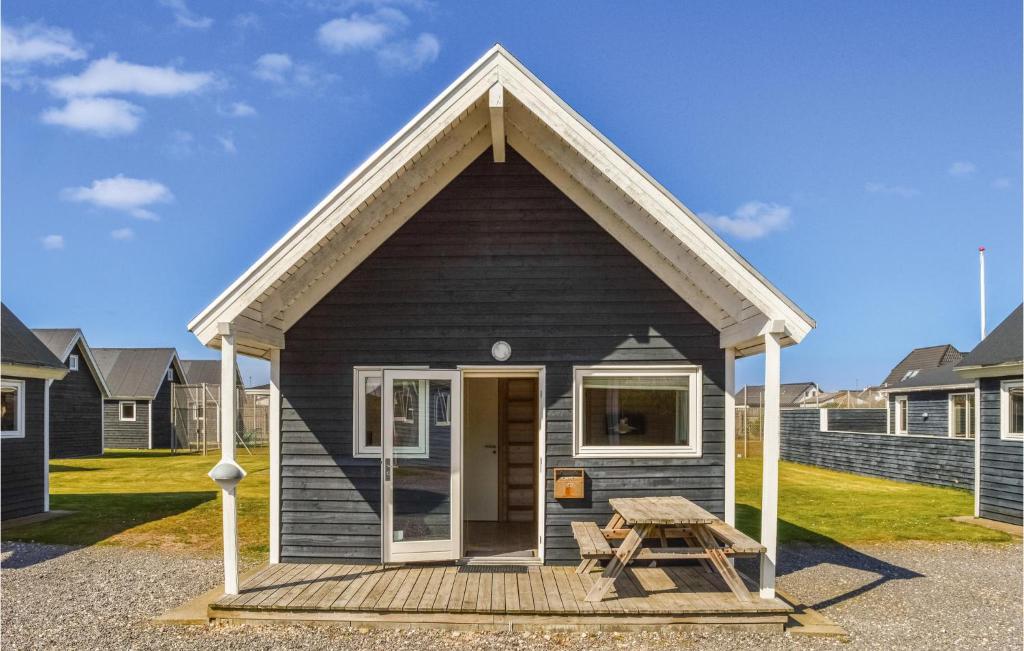 una pequeña casa negra con una mesa de picnic delante en Hytte 4, en Thyborøn