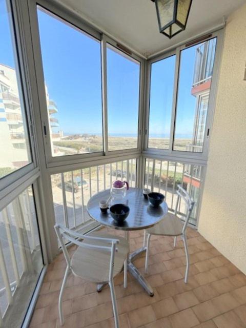 une table et des chaises dans une pièce avec des fenêtres dans l'établissement Confortable Studio cabine - accès plage- vue mer 4TVP38, au Barcarès