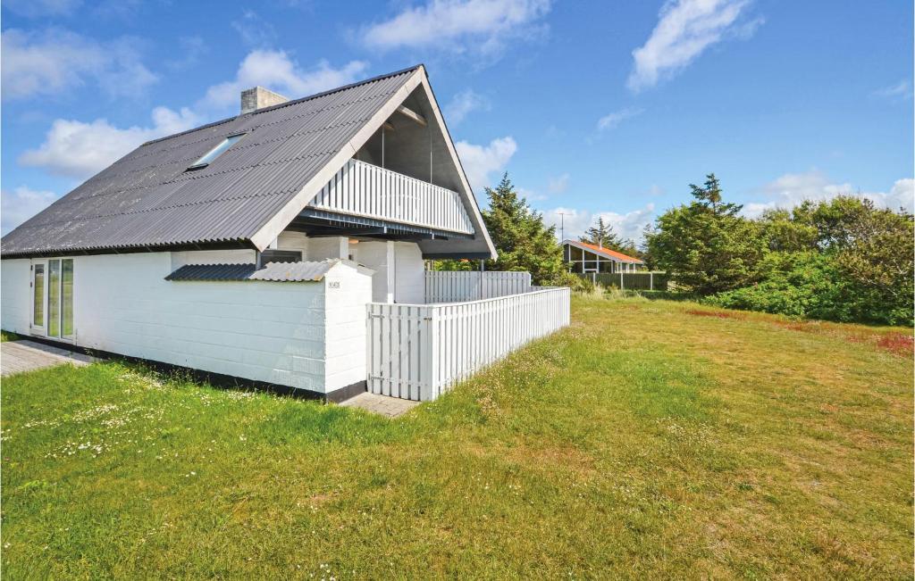 a small white building with a black roof on a grass field at Beautiful Home In Thisted With 3 Bedrooms, Sauna And Wifi in Nørre Vorupør