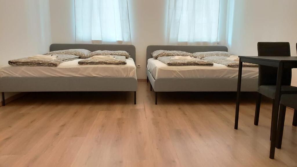 twee bedden in een kamer met een houten vloer bij CozyNite Premium Apartment Hauptbahnhof 1+2 in Wenen