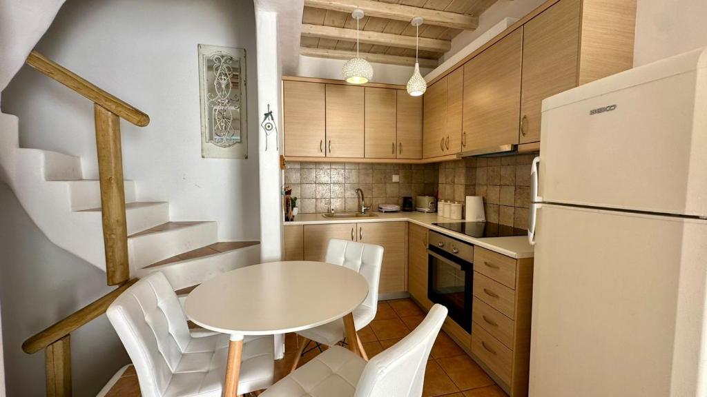 a kitchen with a table and a white refrigerator at Fayrouz Psarrou Beach Mykonos in Mikonos