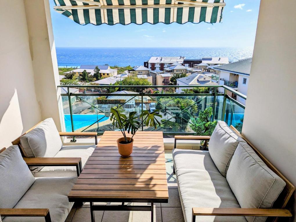 a balcony with a table and a view of the ocean at Sunset Océan - appartement T2 avec vue imprenable sur l'océan et piscine in Saint-Gilles les Bains