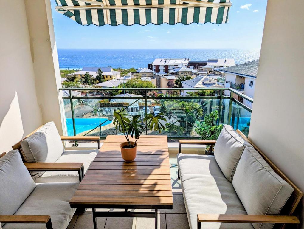 圣吉尔莱班Sunset Océan - appartement T2 avec vue imprenable sur l'océan et piscine的带桌子的阳台，可欣赏海景