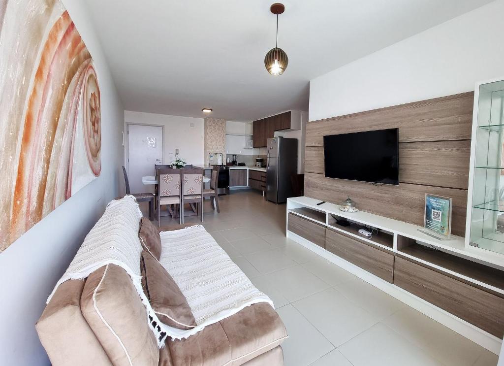 a living room with a couch and a flat screen tv at Areias do Mar ! 2 Quartos Familia com Varanda A213 in Barra de São Miguel