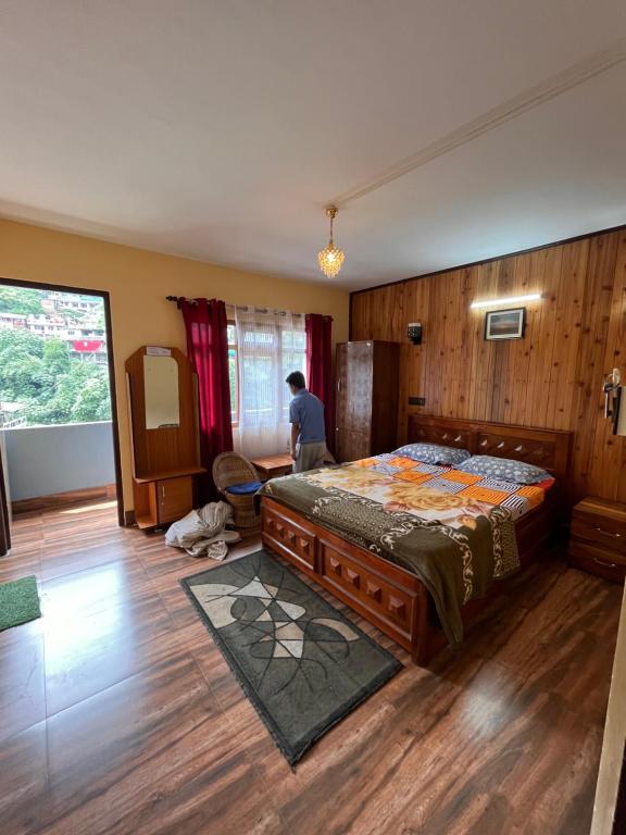 - une chambre avec un lit et une personne assise dans une chaise dans l'établissement Dik's Home, à Darjeeling