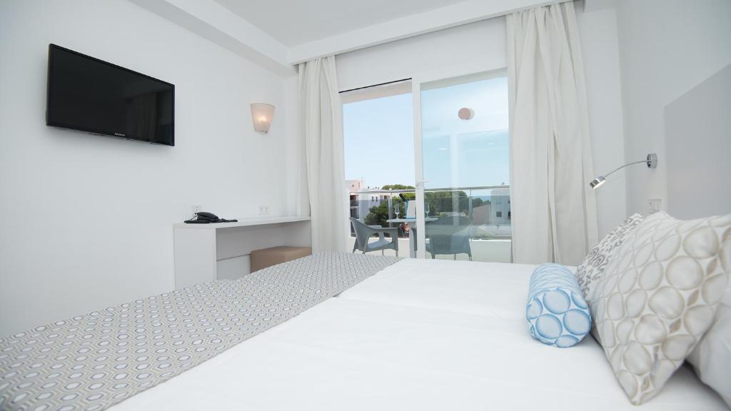 a white bedroom with a large bed and a television at Hotel Chevy & Suites in Cala Ratjada