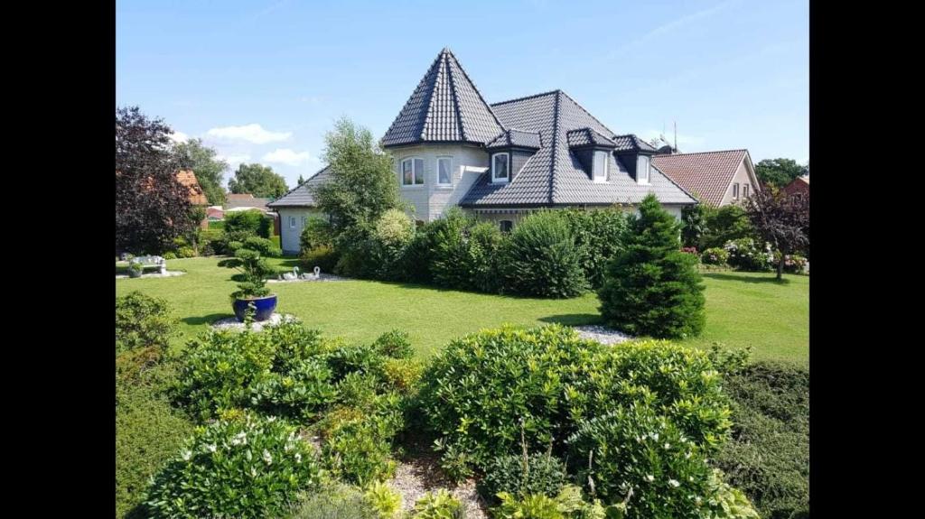 a large house with a large yard with bushes at Ferienhaus Gesine 25193 in Bunde