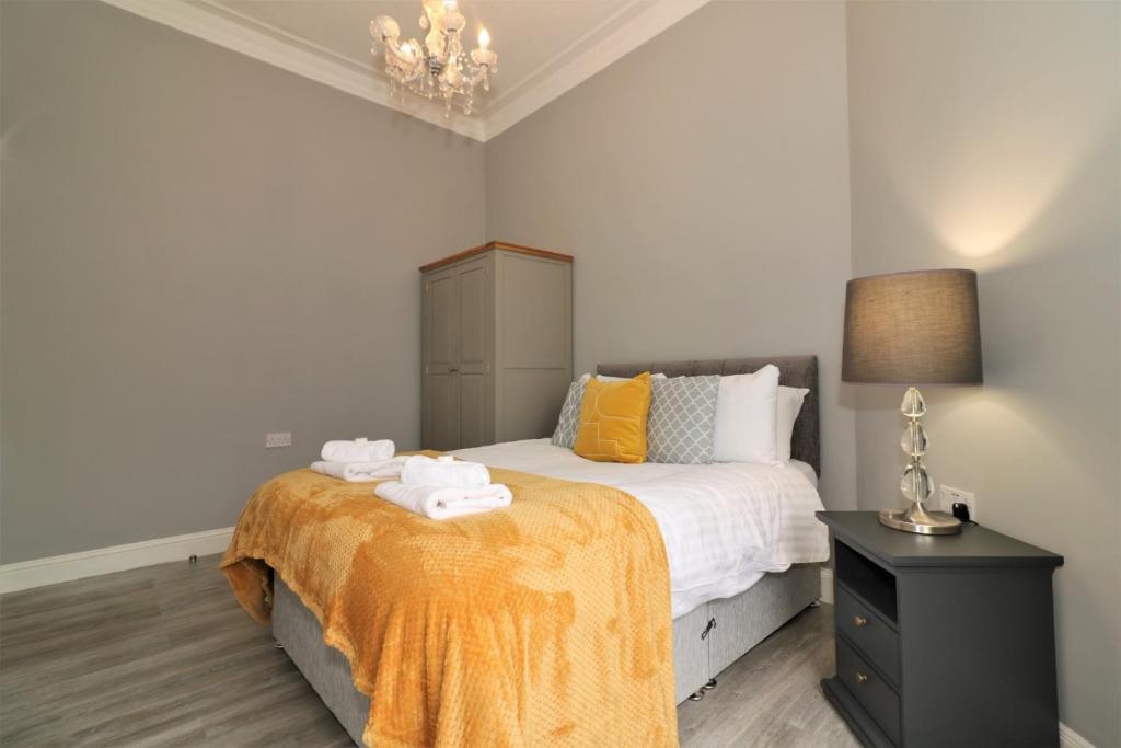 a bedroom with a bed and a nightstand with towels at Signature - Linden House Flat 4 in Airdrie