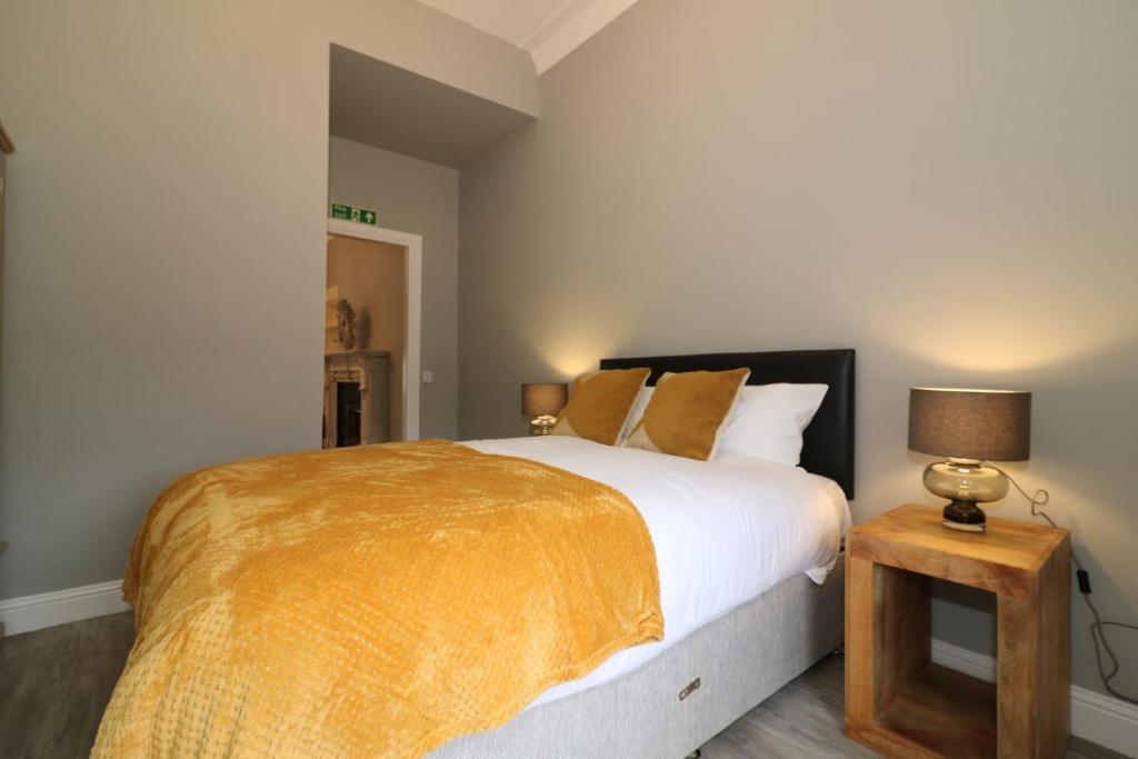 a bedroom with a bed and a table with a lamp at Signature - Linden House Flat 3 in Airdrie