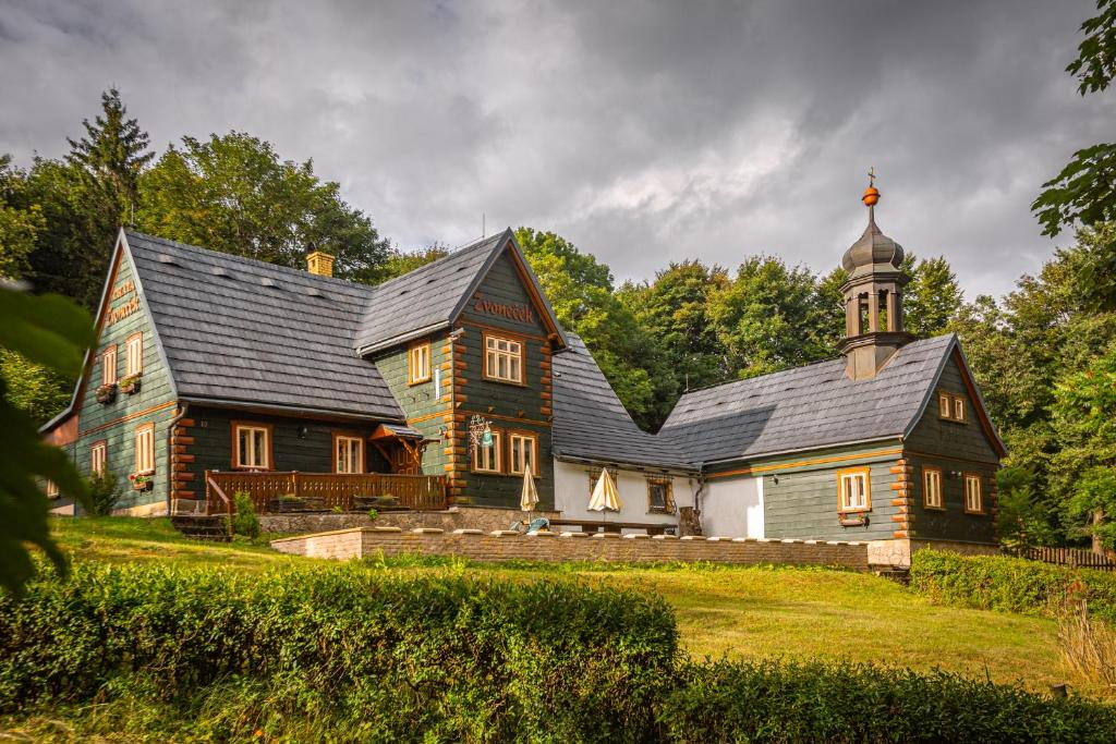 ein großes Haus mit schwarzem Dach und einer Kirche in der Unterkunft Chata Zvoneček in Jiřetín pod Jedlovou