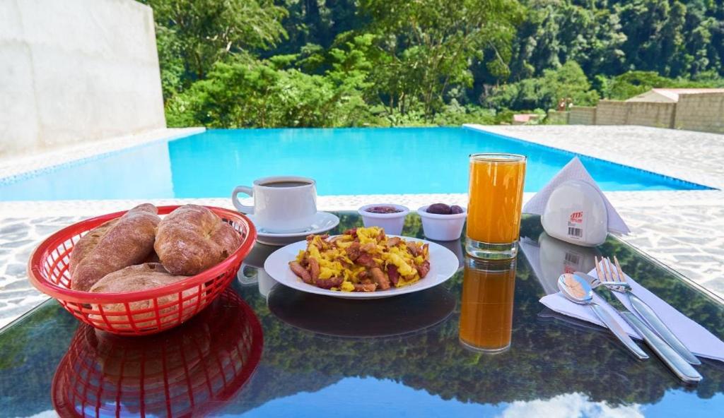 einen Tisch mit einem Teller mit Speisen und Getränken neben einem Pool in der Unterkunft LEMBRANÇAS HOTEL LODGE in Tingo María