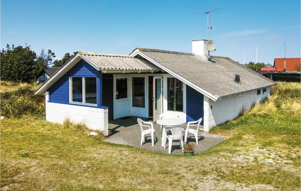 a blue and white house with a table and chairs at Nice Home In Thisted With 3 Bedrooms, Sauna And Wifi in Nørre Vorupør