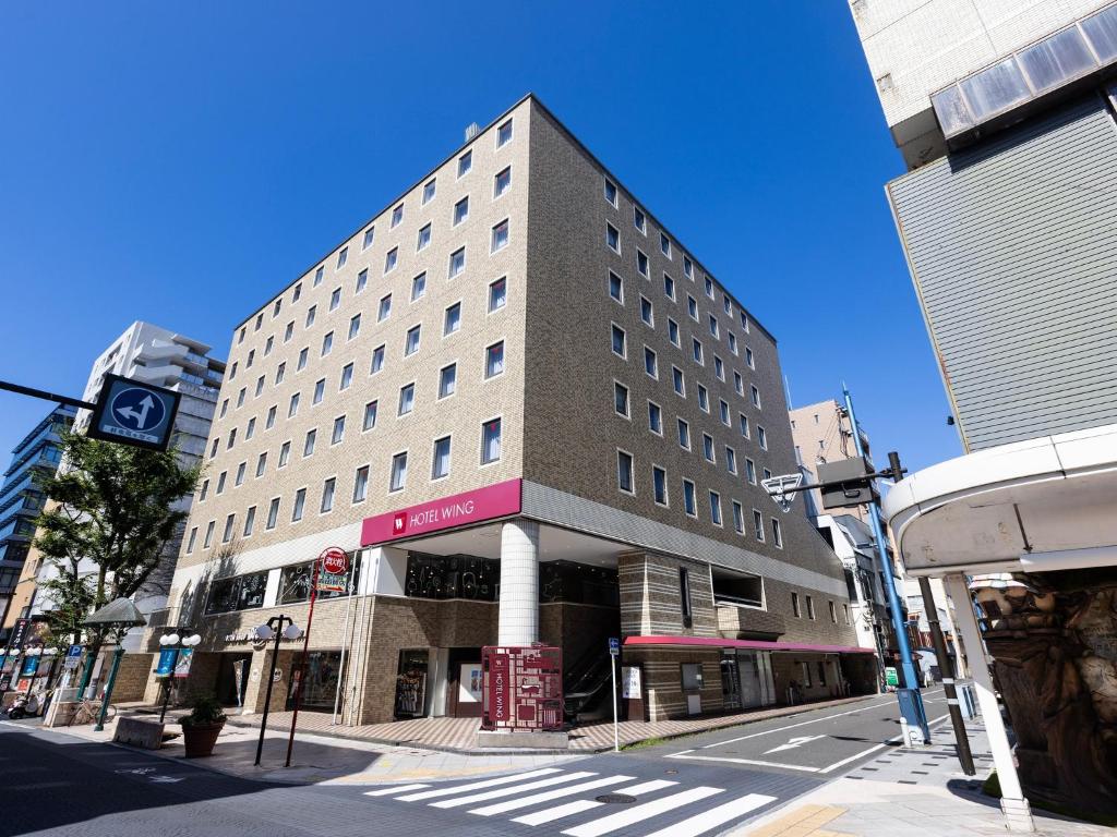 ein hohes Gebäude in einer Stadtstraße mit einem Fußweg in der Unterkunft Hotel Wing International Shizuoka in Shizuoka