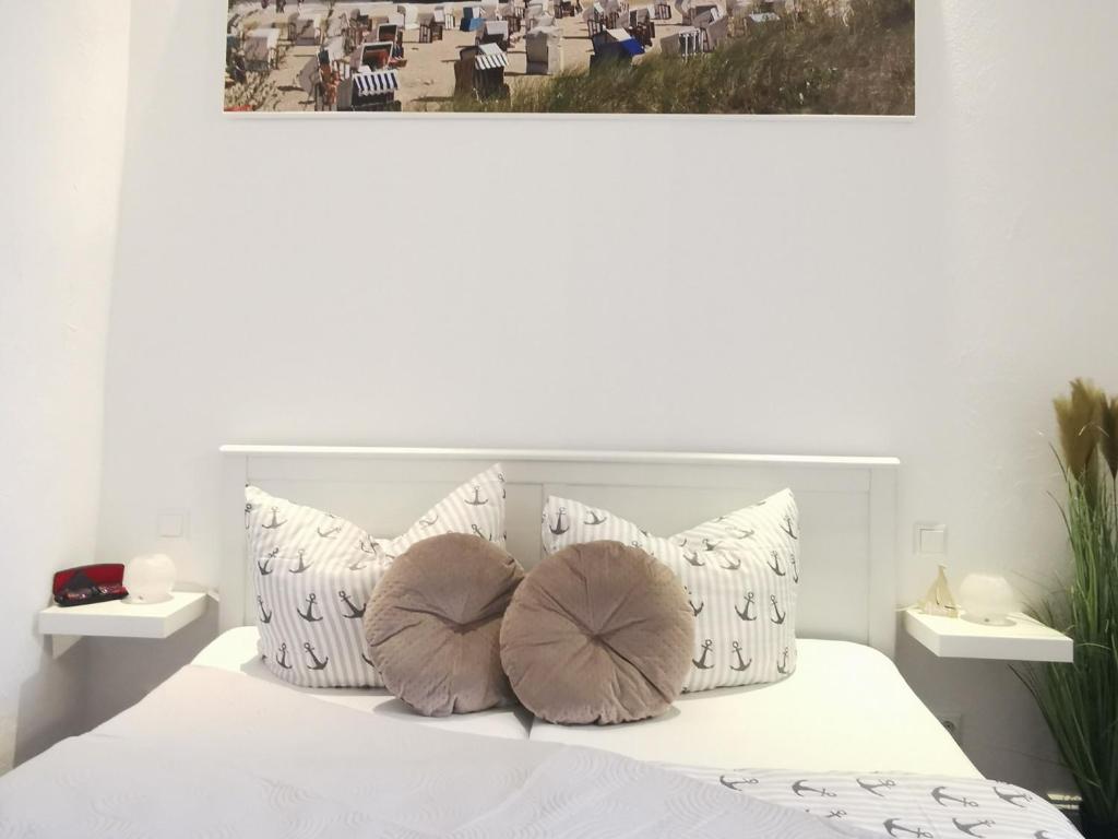 ein weißes Schlafzimmer mit einem weißen Bett und Kissen in der Unterkunft Ferienwohnung MeerZeit Villa Adler in Ahlbeck