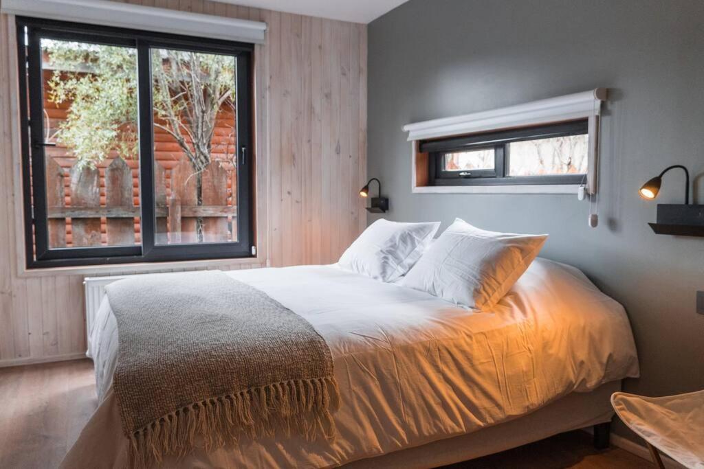 a bedroom with a large bed and two windows at Refugio Simple Sur 6 - 7 personas in Malalcahuello