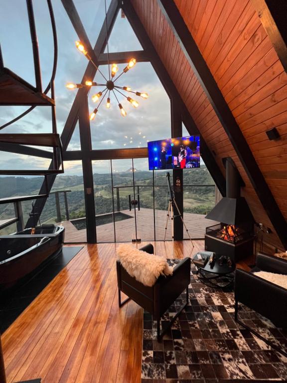 a living room with a tv and a large window at Chalé do Canyon in Barracão
