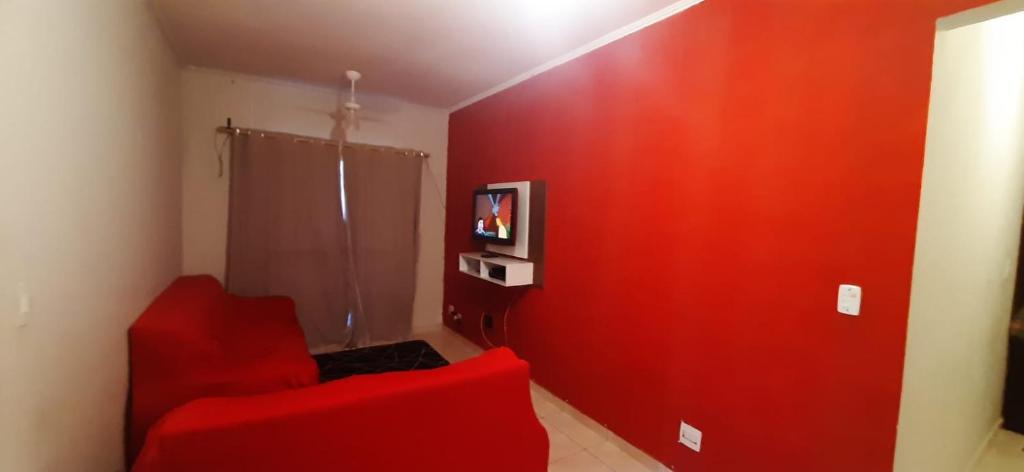 um quarto vermelho com uma parede vermelha e uma cadeira vermelha em Apartamento Praia Mongagua em Mongaguá