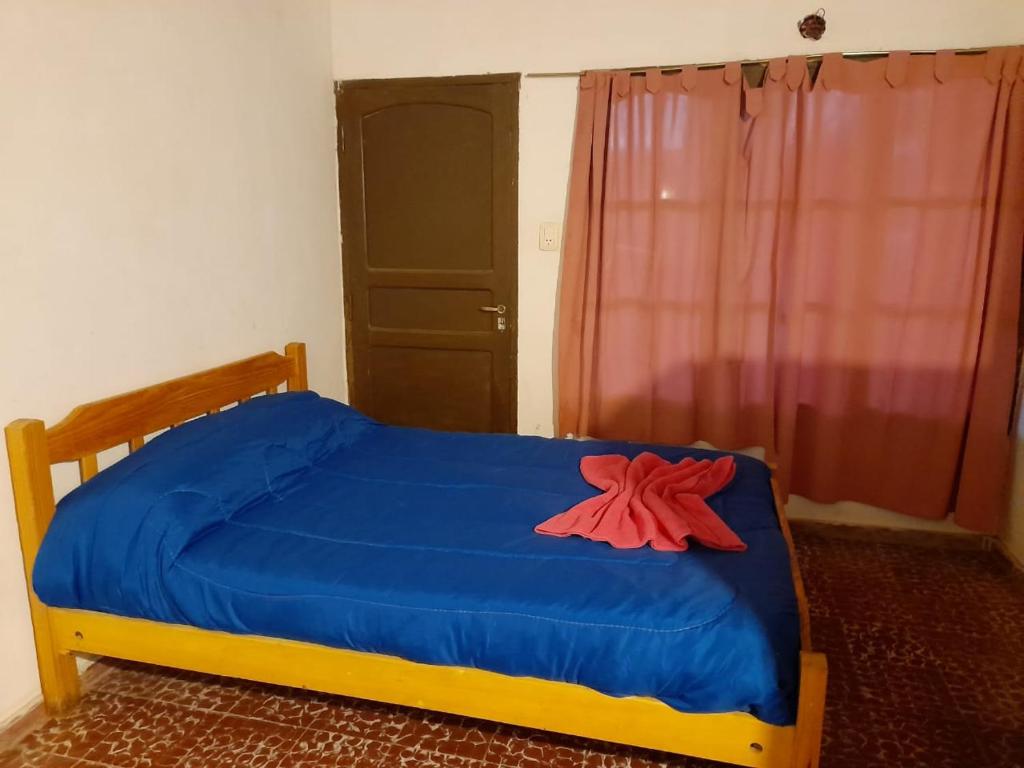 a bedroom with a blue bed with a red flower on it at Fatme Hotel in San Agustín de Valle Fértil