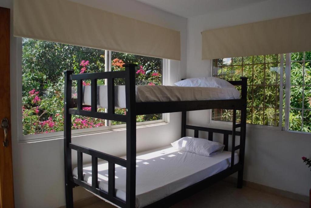 two bunk beds in a room with two windows at HOSTEL LA CASA DE PETRA in Santa Marta