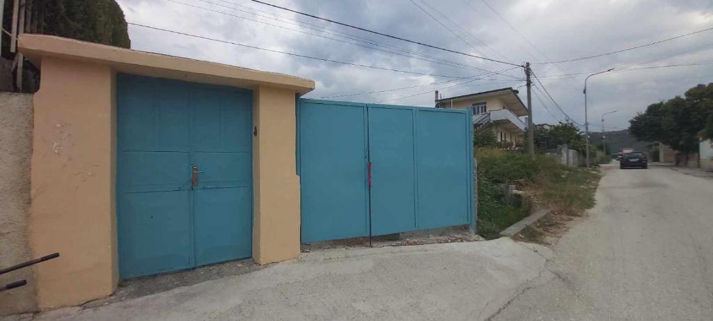 un bâtiment bleu avec des portes bleues sur le côté d'une route dans l'établissement Guest house Aferdita Beqiri, à Berat