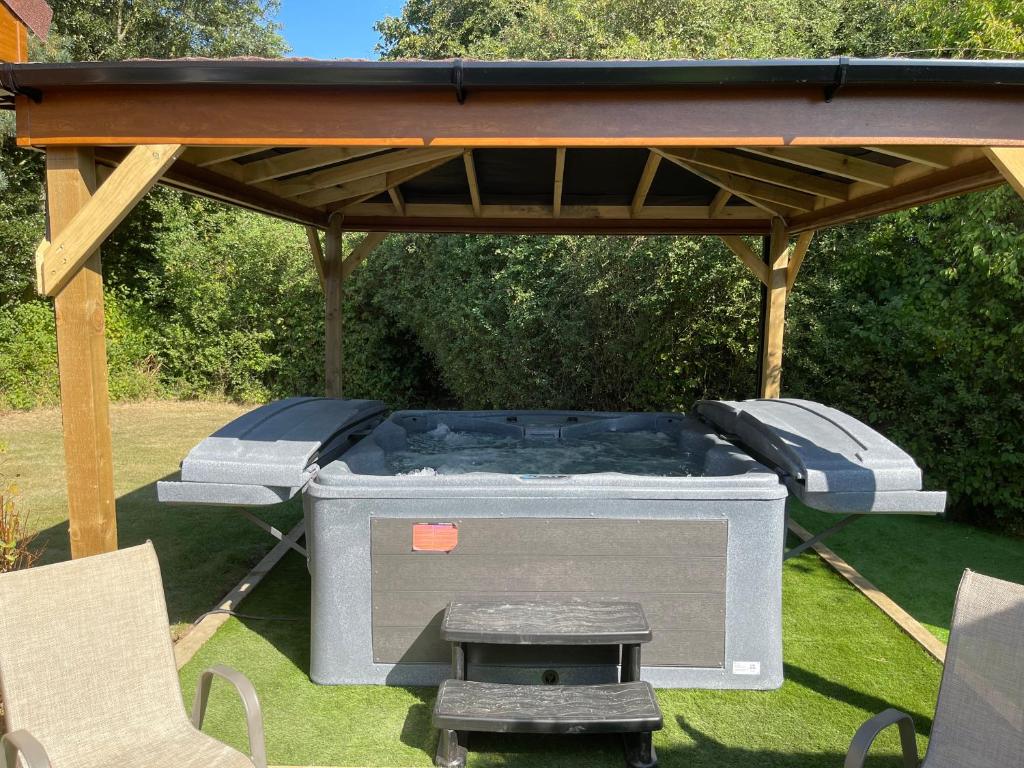 a barbecue grill under a gazebo with a table at Kingfisher Lodge in Grantham