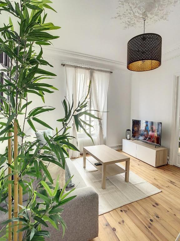ein Wohnzimmer mit einem Sofa und einem Tisch in der Unterkunft Grand Cozy appart - proche métro Paris - proche spots touristiques in Ivry-sur-Seine