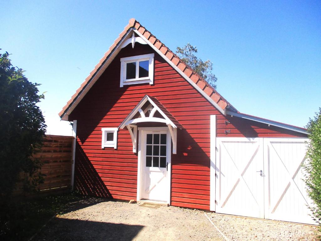 un garaje rojo y blanco con una puerta blanca en Cottage Lillstugan proche de la Baie de Somme, en Quesnoy-le-Montant