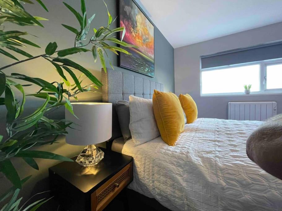 een slaapkamer met een bed met gele kussens en een plant bij Luxury 1 bed Flat + sofa bed- Dudley 