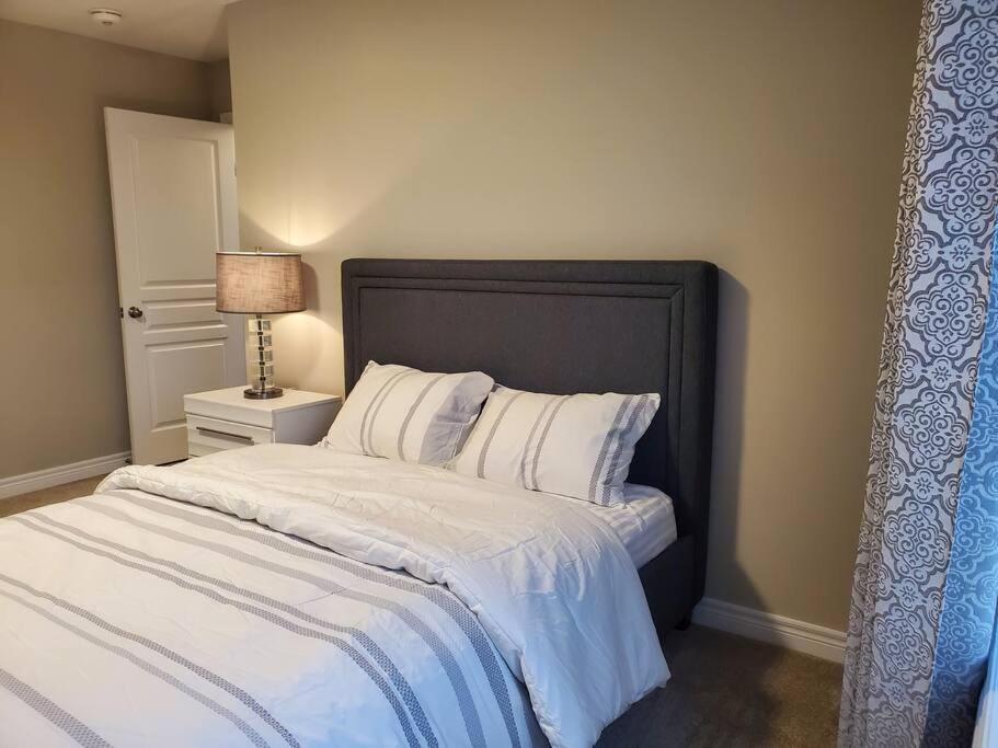 una camera da letto con un letto con lenzuola bianche e una lampada di 4 BD Family Retreat a Stratford