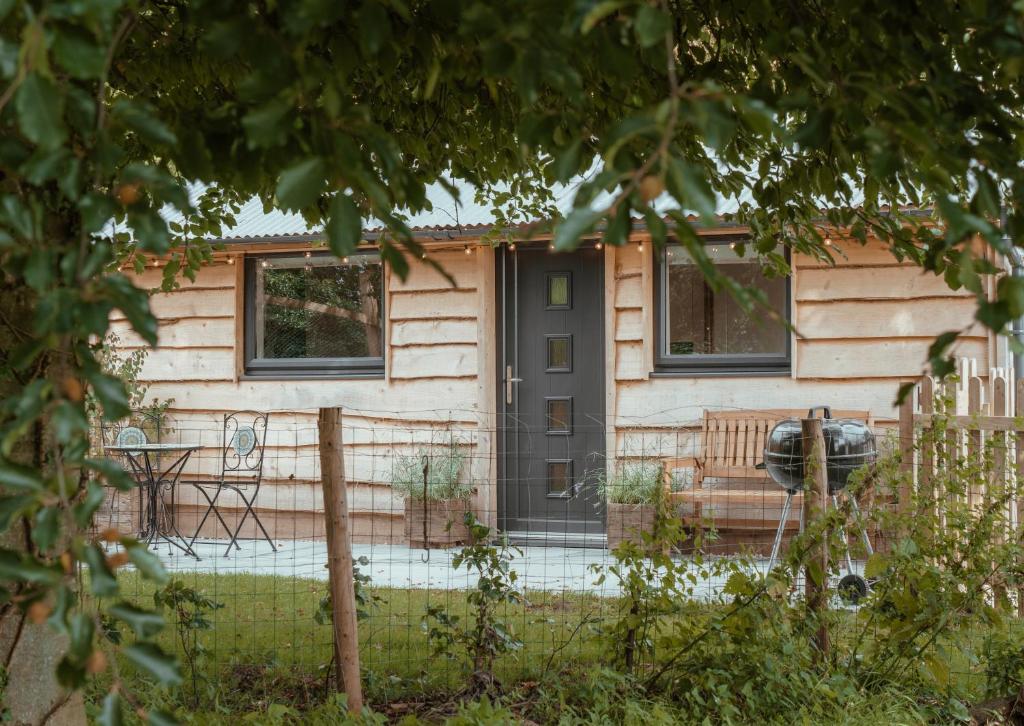 une maison avec une porte noire et une clôture dans l'établissement Rose Hideaway - Forest of Dean Cosy Cabin Retreat, à Yorkley