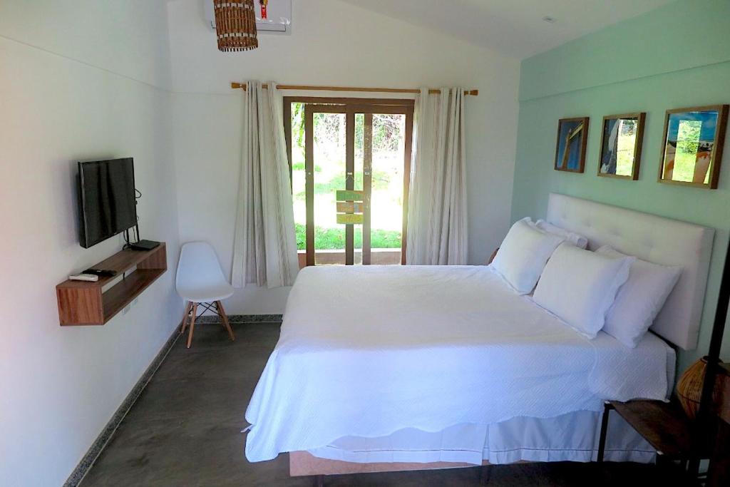 a bedroom with a white bed and a television at Refúgio Integração in Mata de Sao Joao