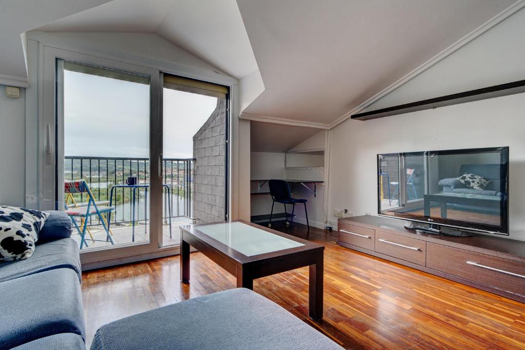 a living room with a couch and a large window at Luminoso ático con terraza, Irún in Irún