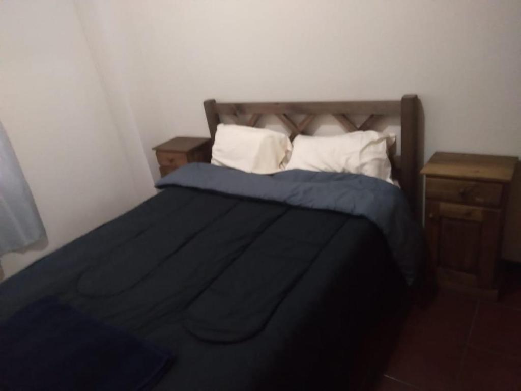 1 cama con edredón azul y 2 mesitas de noche en Departamento céntrico en Mendoza