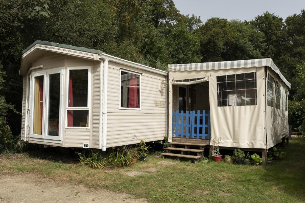 a white house and a shed in the grass at Mobilhome tout équipé in Quimper