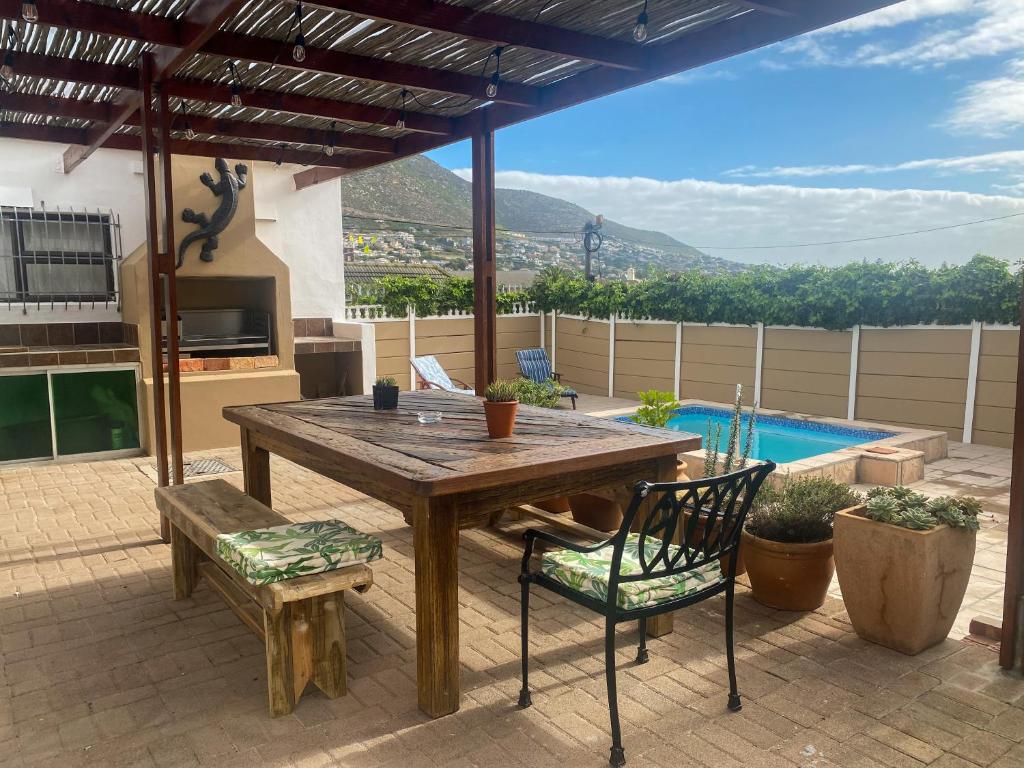 patio con mesa de madera, sillas y piscina en Crescent Corner Vacation Home, en Ciudad del Cabo