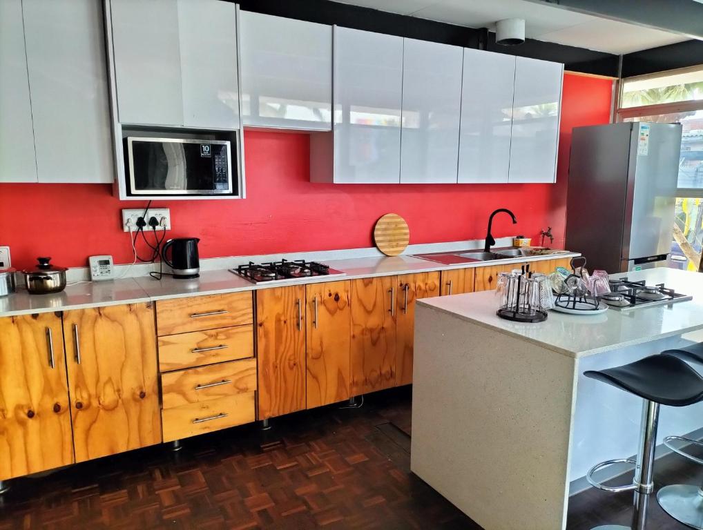 a kitchen with wooden cabinets and a red wall at Inkanyezi guest house in Durban