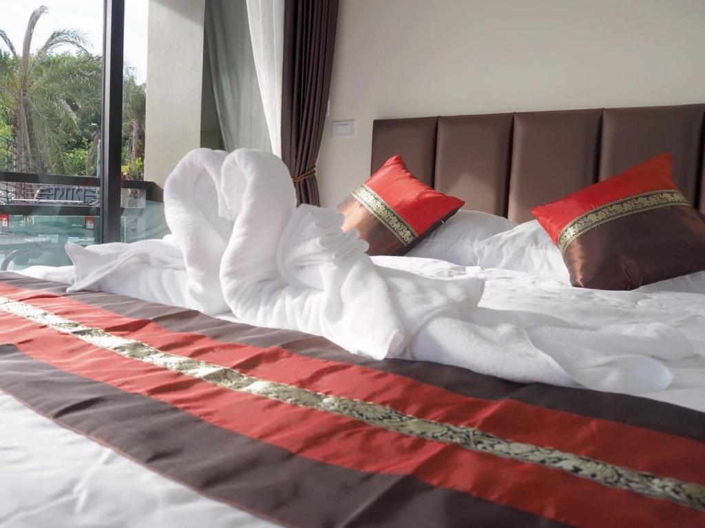 a bed with white sheets and red pillows at Triple O Phala Beach in Ban Phala