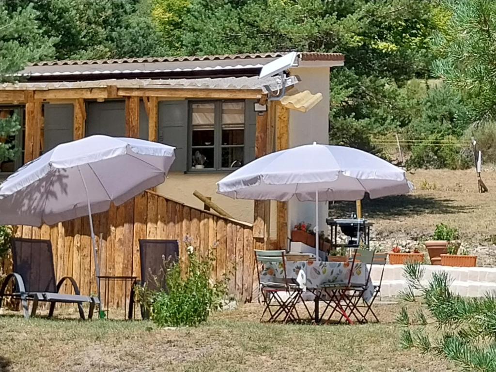 dois guarda-sóis e cadeiras em frente a uma casa em Petit studio dans la prairie em Saint-Auban