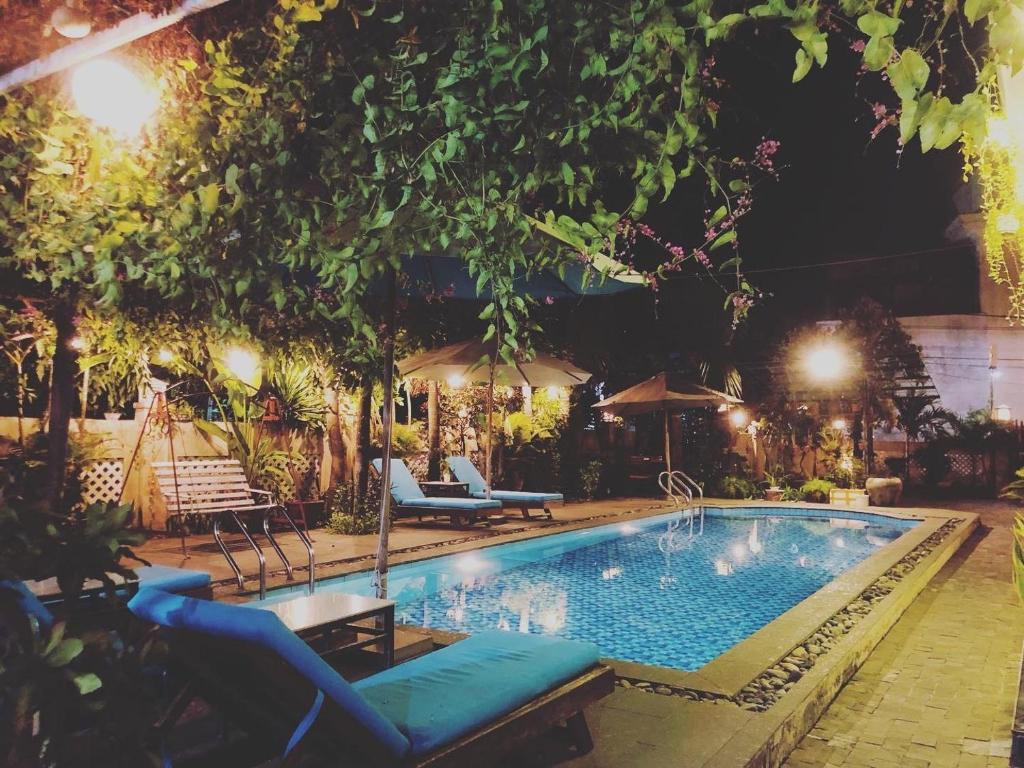 ein Pool mit Stühlen und Sonnenschirmen in der Nacht in der Unterkunft Gia Lam Villa Hoi An in Hoi An
