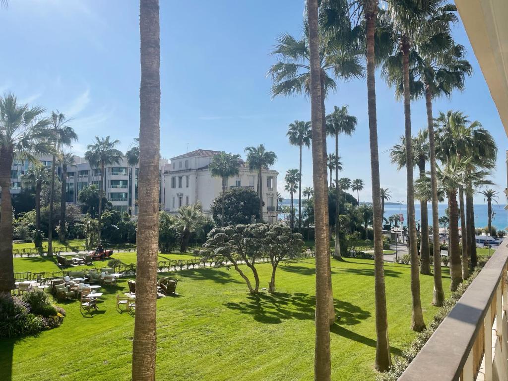 - une vue sur un parc avec des palmiers et un bâtiment dans l'établissement Studio Cannes Grand Hôtel Cormoran avec Terrrasse, à Cannes