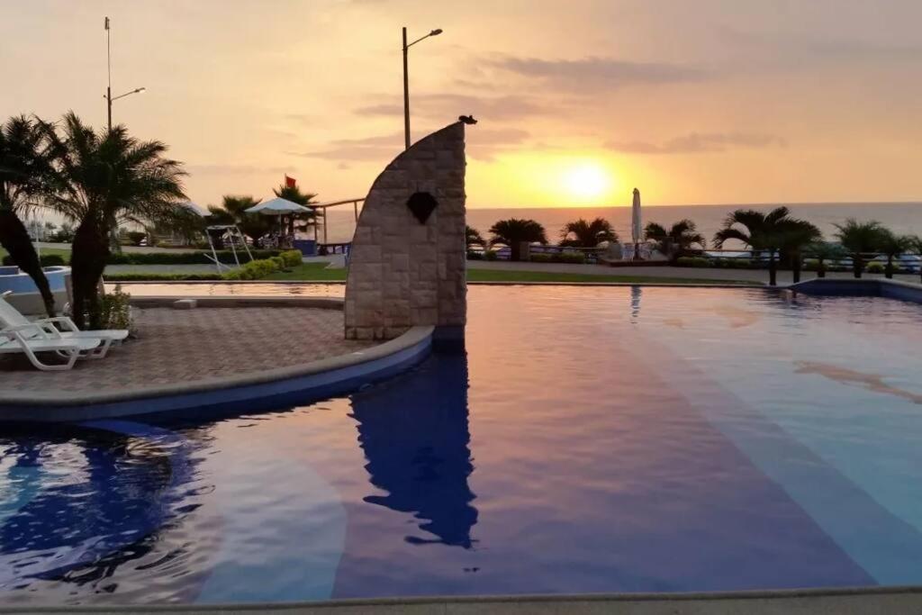 una piscina con puesta de sol en el fondo en Lujoso Condominio Frente al Mar en Tonsupa, Ecuador, en Tonsupa