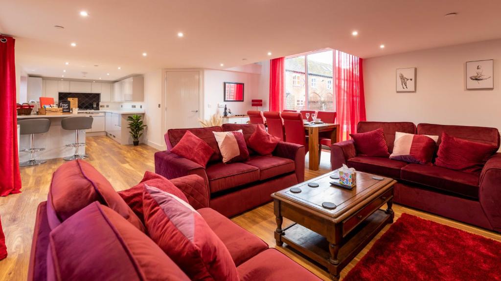 a living room with red couches and a table at Cariad - Spacious 3 bed, group getaway Luxury Cottage with Private Hot Tub in Denbigh