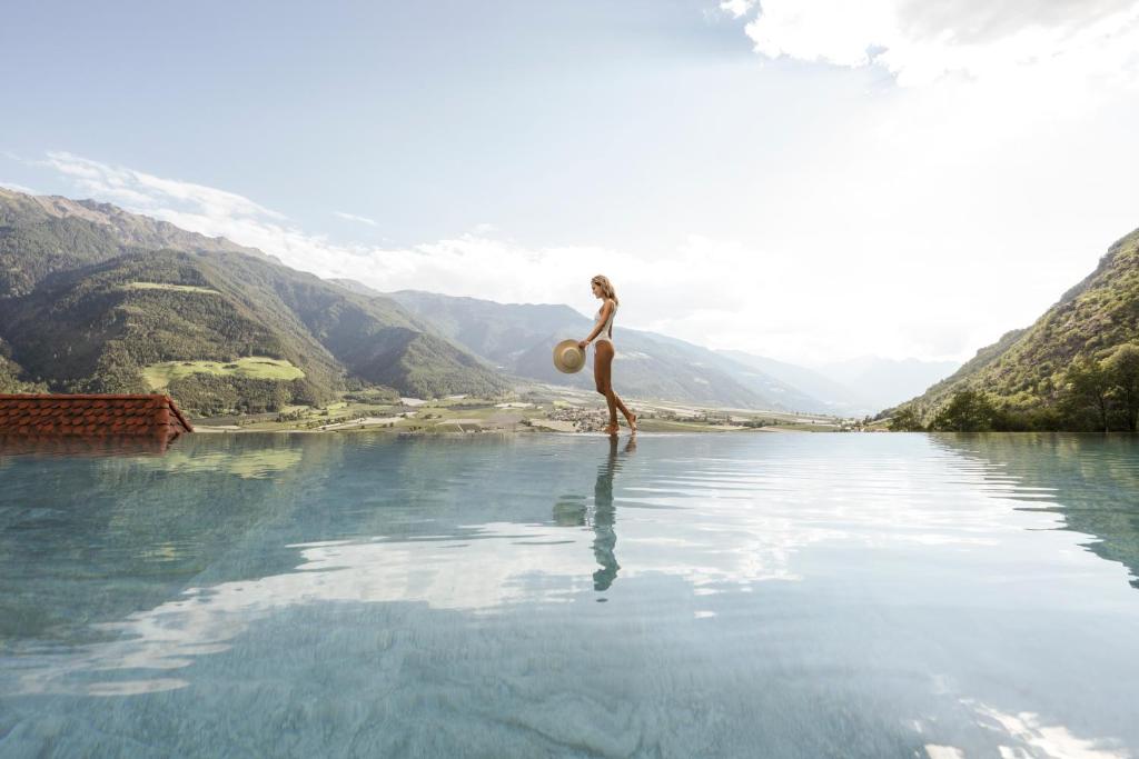 une femme debout dans une masse d'eau dans l'établissement Preidlhof Luxury Dolce Vita Resort, à Naturno