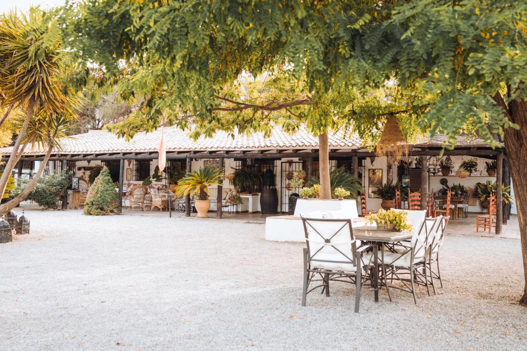 un patio con mesa y sillas bajo un árbol en LA CUADRA, Finca a los pies de Sierra Nevada, a 10 minutos del centro, Piscina, Jardín, Barbacoa, en La Zubia