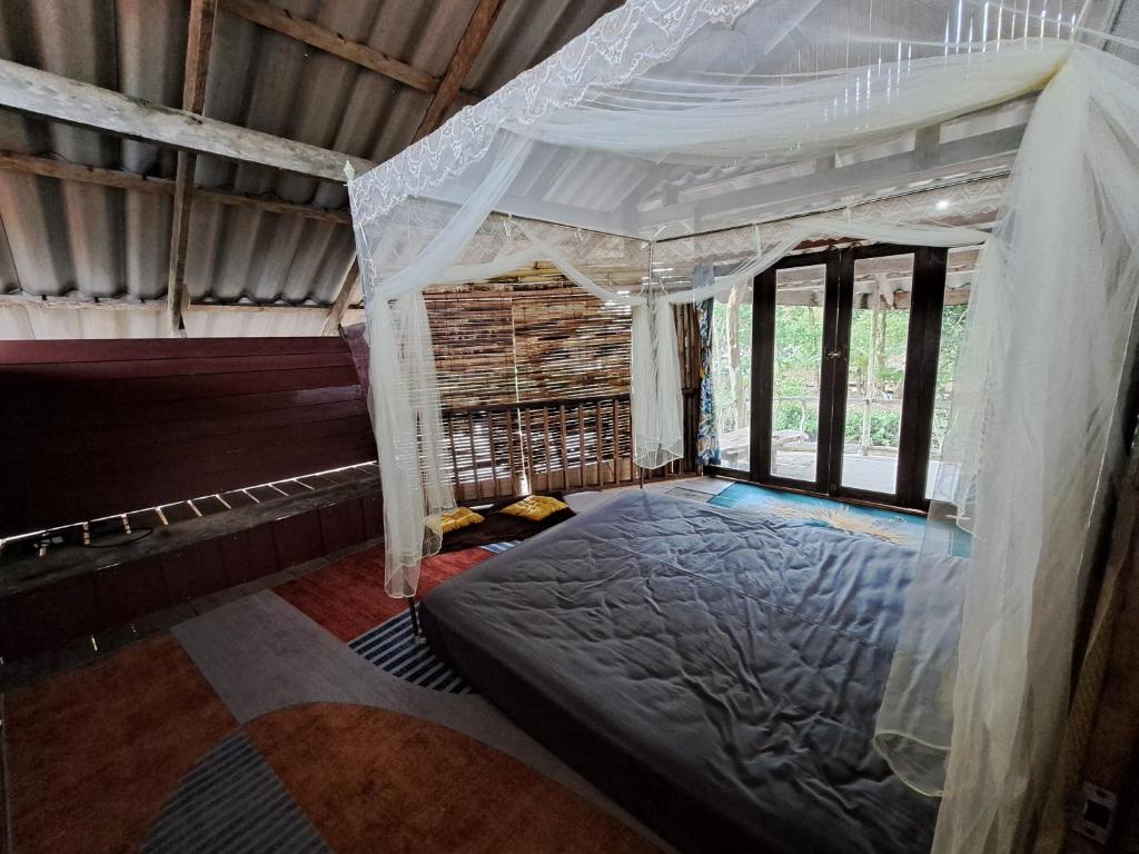 ein Schlafzimmer mit einem Himmelbett in einem Zimmer mit Fenstern in der Unterkunft Big Hug Home-Nok kao house in Ko Yao Noi